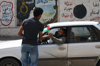 صورة برعاية بال ثينك للدراسات الاستراتيجية: العمال يوزعون اعلام فلسطين تعزيزاً للمصالحة